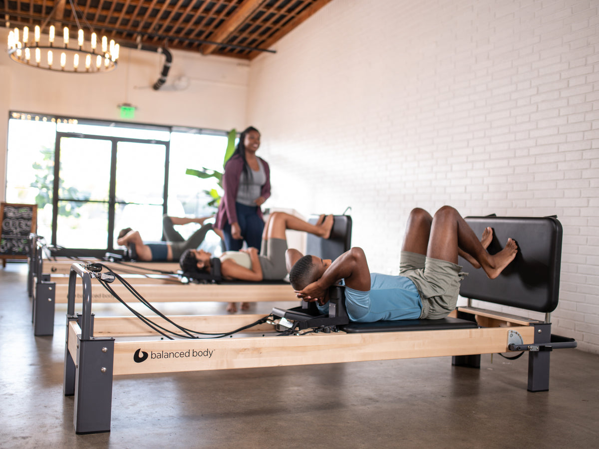 Balanced Body Padded Jumpboard on the Rialto Reformer, used in a Pilates group class with multiple participants